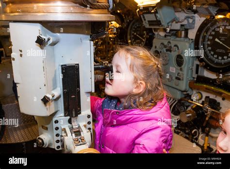 Child / kid / girl looking through periscope & interior / inside control room of HMS Alliance ...