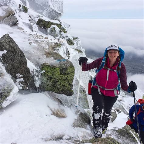 a woman hiking up the side of a snow covered mountain