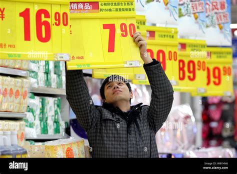 A Chinese employee changes a price tag at a supermarket in Nantong city ...