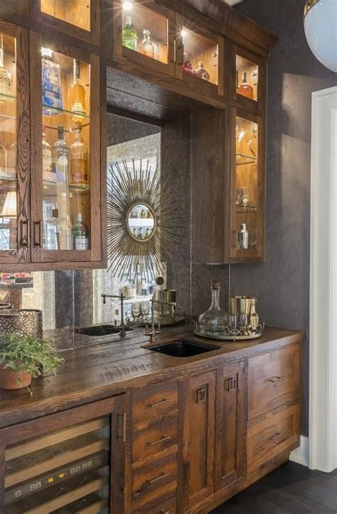 Rustic wet bar features rustic cabinets fitted with a glass-front wine cooler paired with ...