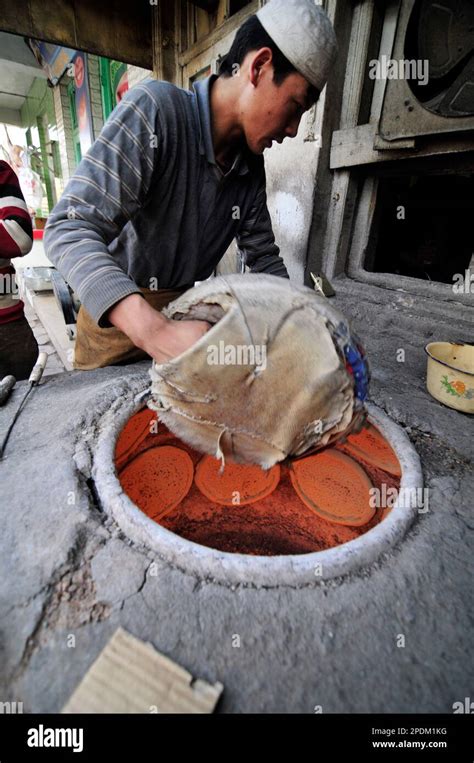 An Uyghur man baking the Naan bread in a tandoor oven in the old city of Kashgar, Xinjiang ...