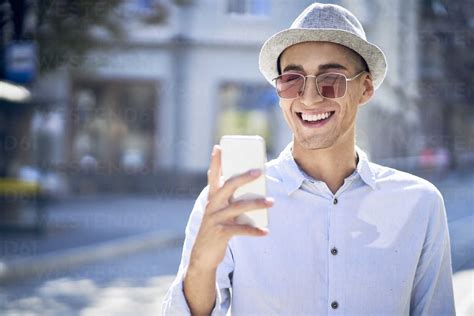 Happy young man looking at cell phone in the city stock photo