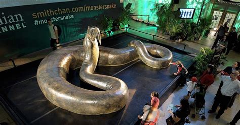 a group of people standing in front of a giant metal snake on top of a table