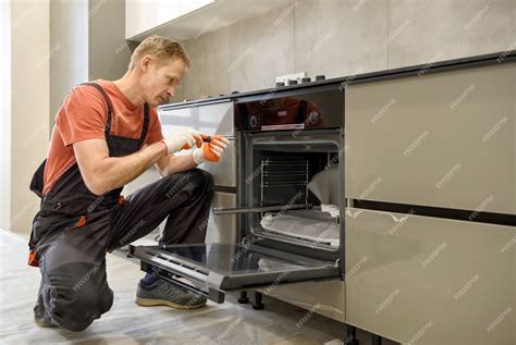 Premium Photo | Worker installing an electric oven in the kitchen furniture