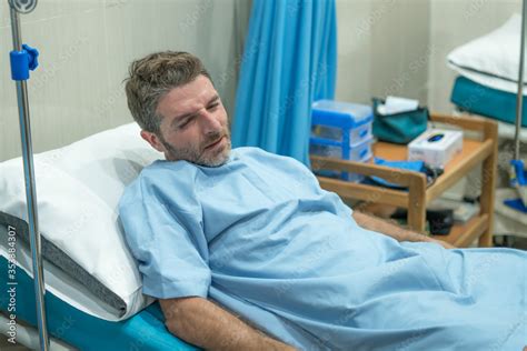 scared and worried man in pain at hospital room - attractive injured man lying on bed suffering ...