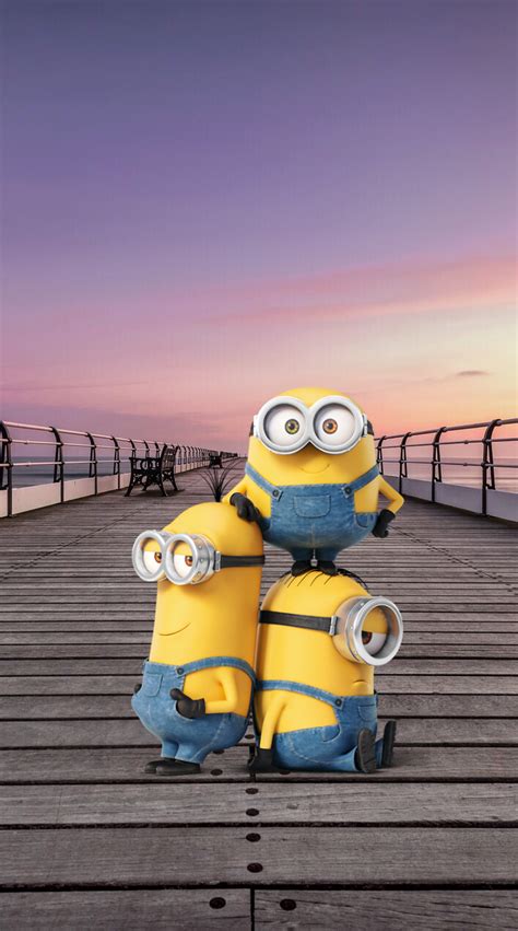 two minion sitting on top of each other in front of the ocean at sunset