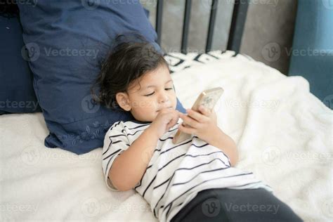 Side view of focused child boy using smartphone playing and lying on a bed 26538083 Stock Photo ...