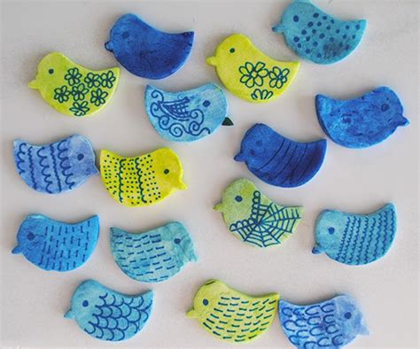 several small blue and yellow birds on a white surface