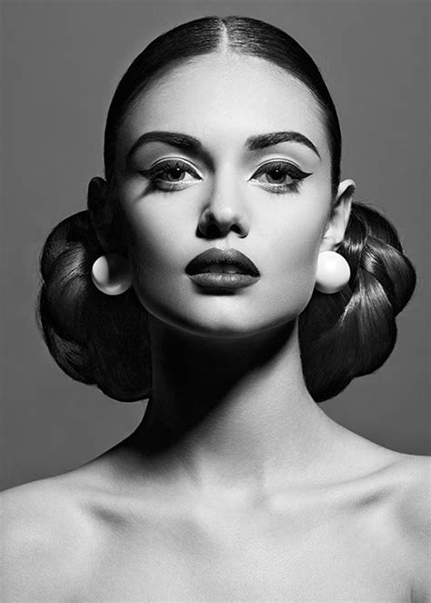 a black and white photo of a woman's face with her hair in buns