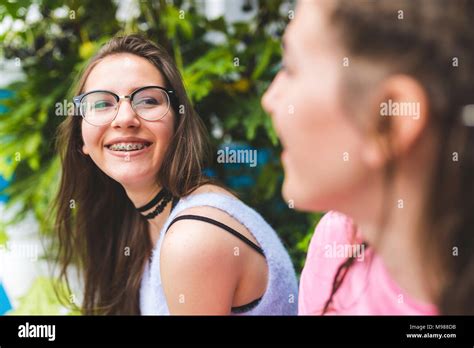 Happy teenage girl with braces and glasses looking at friend Stock ...