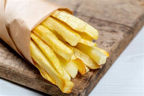 French fries in a paper wrapper on wooden board - Creative Commons Bilder