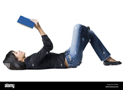 Woman lying down with hardcover book reading Stock Photo - Alamy