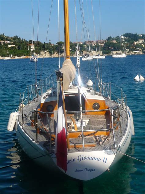 a sailboat in the water with other boats in the background on a sunny day