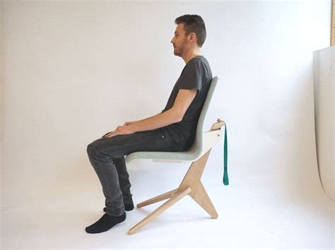 a man is sitting on a chair in front of a white wall and looking away from the camera