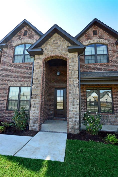 Brick and stone exterior featuring stone archway, dark bronze windows and 6 lite 8' entry door ...