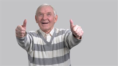 Happy grandfather with two thumbs up. Cheerful eldery man giving thumbs up sign on grey ...