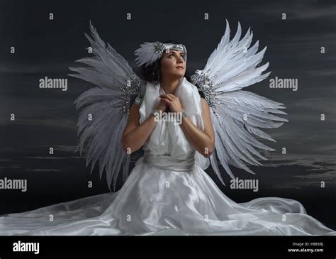 Young beautiful woman in white dress with angel wings on black background Stock Photo - Alamy