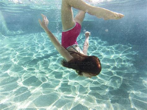 Image of Girl swimming underwater in a pool - Austockphoto