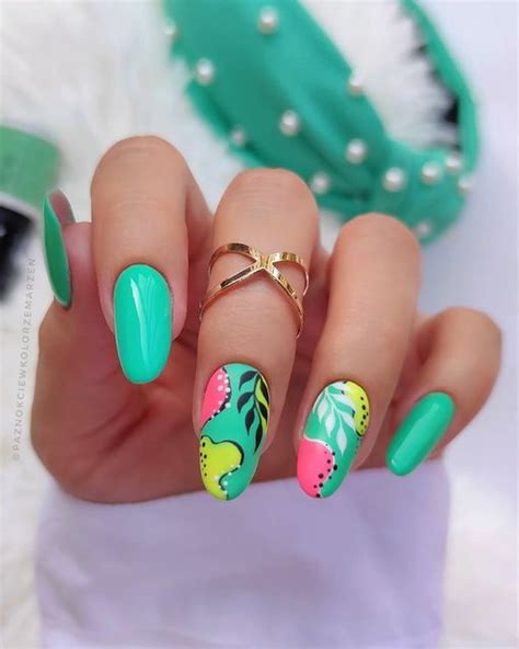 a woman's hand with green and pink nail polishes on her nails, holding ...