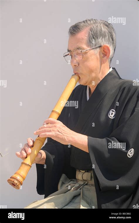 Japanese man playing the Japanese bamboo flute on the banks of the Kamo river, Kyoto, Japan ...