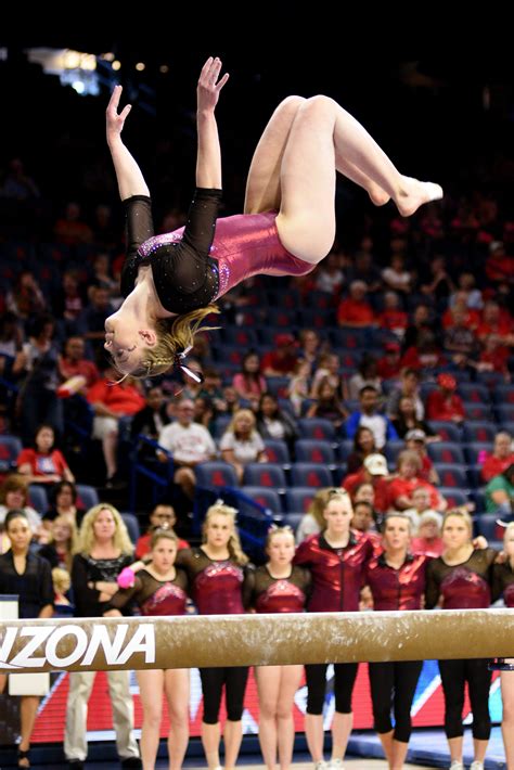 University of Denver gymnast Rachel Fielitz competes a back tuck on beam as teammates look on ...