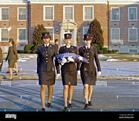 Three female Marines, in dress blue uniforms, raise the morning colors ...