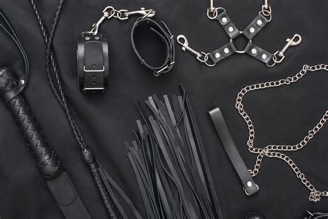 50 Shades of Grey. Top view of bdsm leather kit (whips, handcuffs, mask and chain) against of a ...