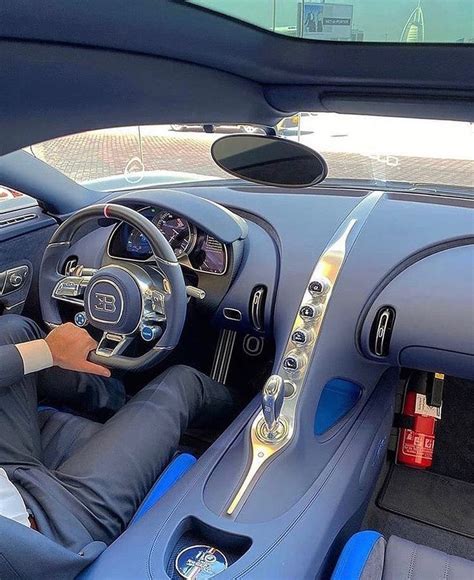 a man sitting in the driver's seat of a blue sports car with his hands on the steering wheel