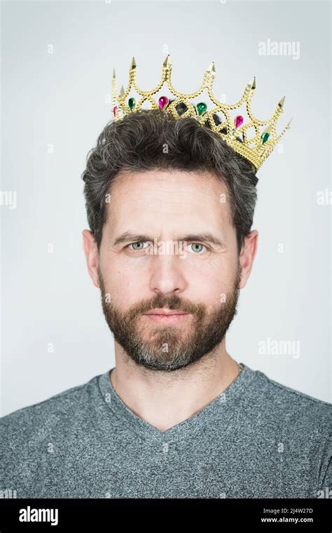 Young man with golden crown of king over gray background. Handsome successful man wearing king ...