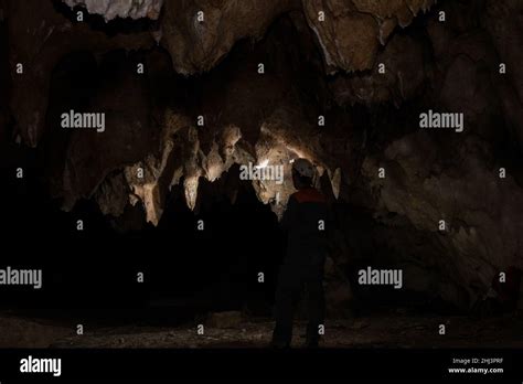 Male speleologist with helmet studying the walls of the dark cave Stock ...