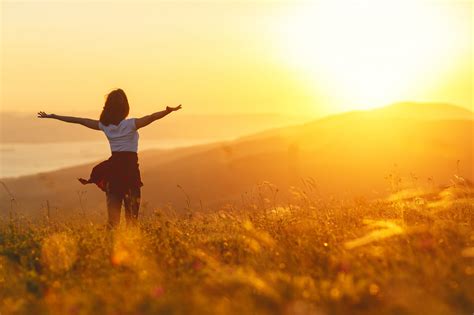 Happy woman standing with her back on sunset in nature iwith open hands – YGYI