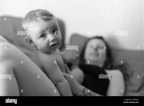 Mother and baby son joyful intimacy. Baby sitting on his mother's belly and looking at camera ...