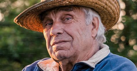 Portrait of an elderly gray-haired man in a straw hat on a background ...