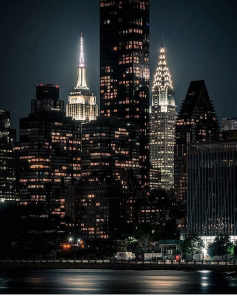 the city skyline is lit up at night, with skyscrapers in the foreground