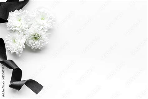 Funeral symbols. White flower near black ribbon on white background top ...