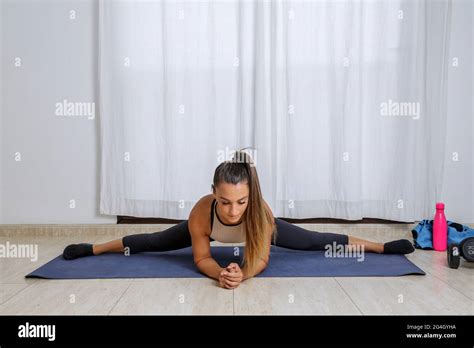 Full body of young flexible female in activewear performing Side Splits ...