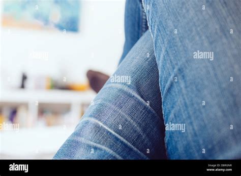 Woman legs crossed wearing blue jeans relaxing on coach in a white room Stock Photo - Alamy