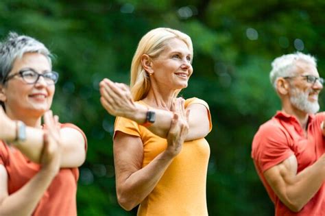 Premium Photo | Group of happy senior people training outdoors stretching arm muscles