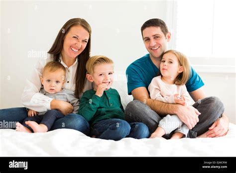 Portrait of family with three children (2-3, 4-5) sitting on bed Stock Photo - Alamy