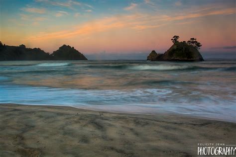 an ocean beach with waves crashing on the sand and small islands in the ...