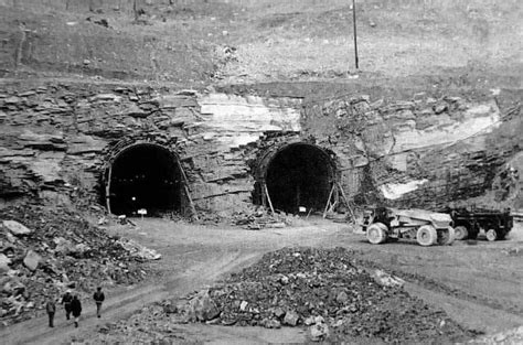 an old black and white photo of two men walking in front of a tunnel that is being built into ...