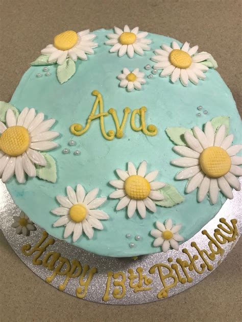 a birthday cake decorated with daisies and the name ava