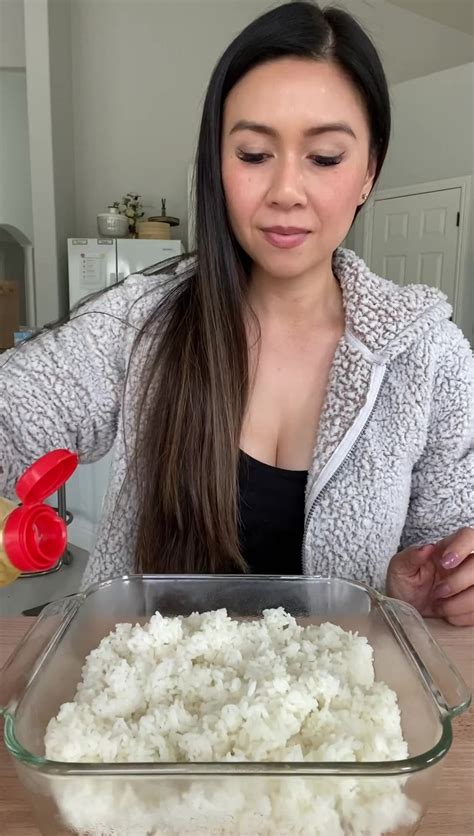 a woman standing in front of a glass pan filled with rice on top of a wooden table