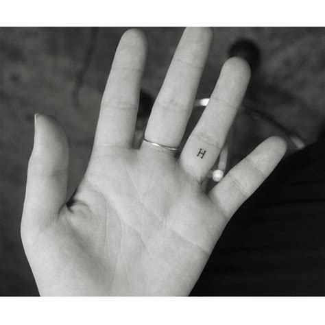 Minimalistic letter "H" tattoo located on the finger.