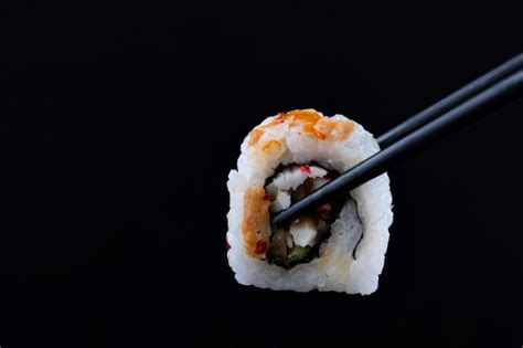 Premium Photo | Sushi with black chopsticks on black background