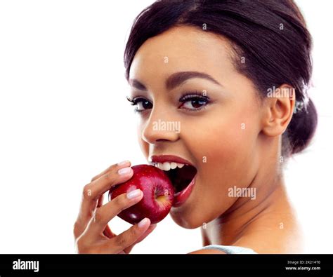Biting into her favorite snack. Studio portrait of a young woman biting into an apple Stock ...