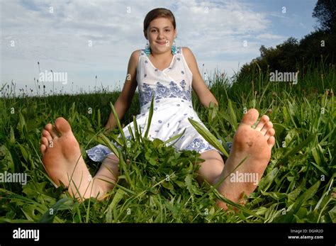 Teenage girl wearing a dress sitting with bare feet in the grass Stock Photo - Alamy