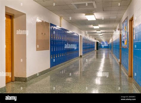 Typical, nondescript USA empty school hallway with blue metal lockers ...