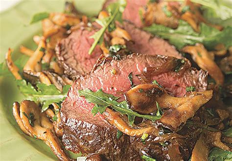 a green plate topped with steak and mushrooms on top of it's side dish