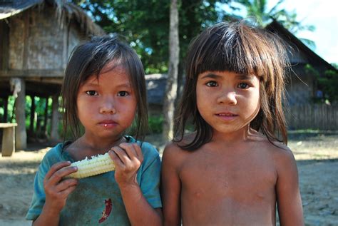 Two young girls snack on sweetcorn in a village deep in the hills of Laos, near Luang Prabang ...